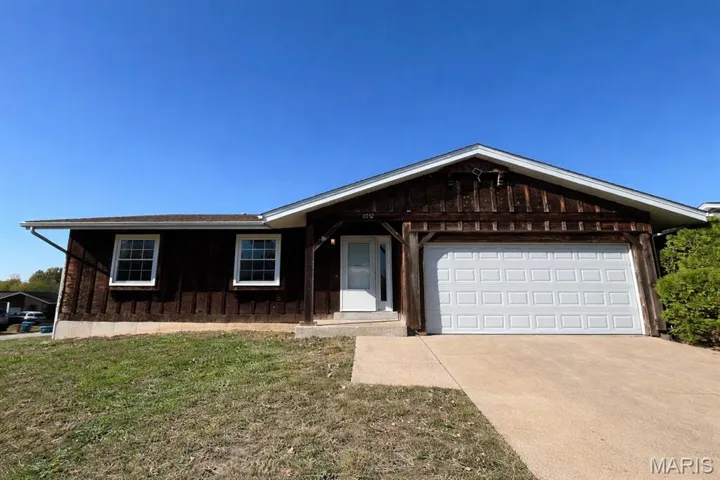 Ranch-style house with driveway, a front lawn, and a garage