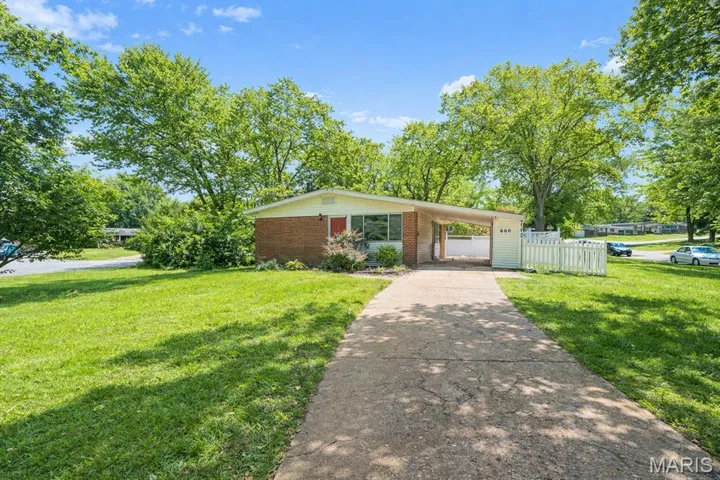 View of front of home with driveway, an attached carport, and brick siding