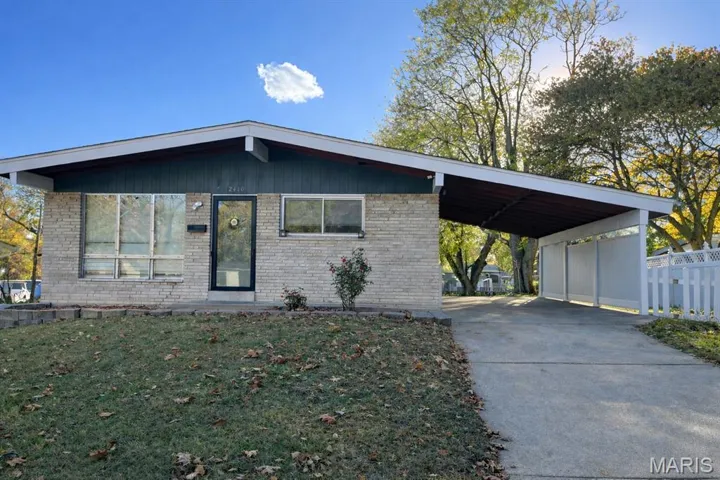 Mid-century home featuring driveway, brick siding, and an attached carport