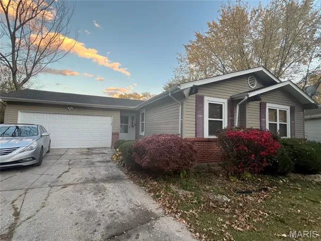 View of front facade with brick siding, driveway, and an attached garage