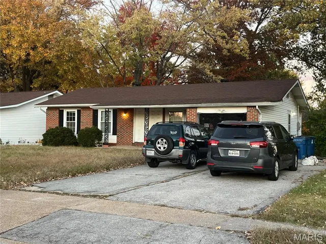 Single story home with brick siding, driveway, and a front lawn