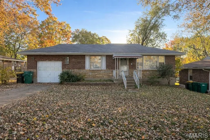 View of front of house featuring driveway, stone siding, a garage, and brick siding
