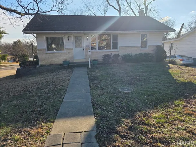View of front of property with brick siding, a front lawn, and a chimney