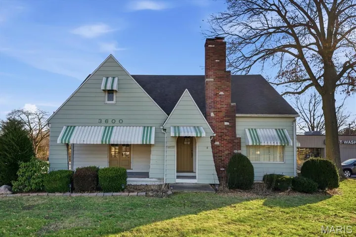 Bungalow featuring a chimney, a front lawn, and a shingled roof