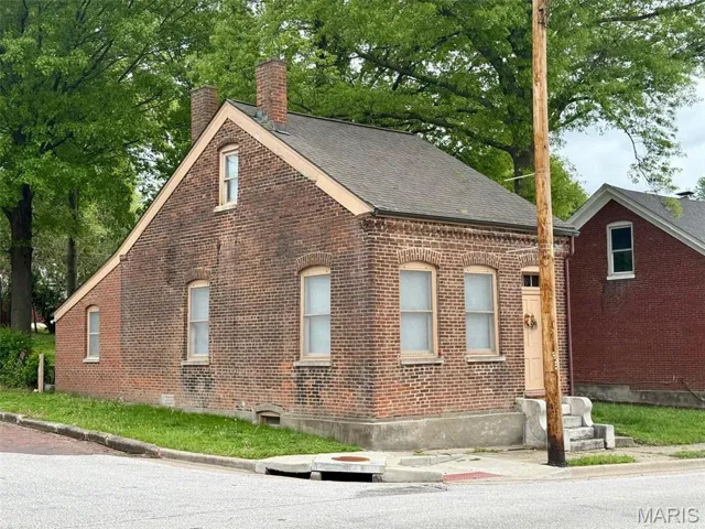 View of side of home with a chimney, brick siding, and a shingled roof
