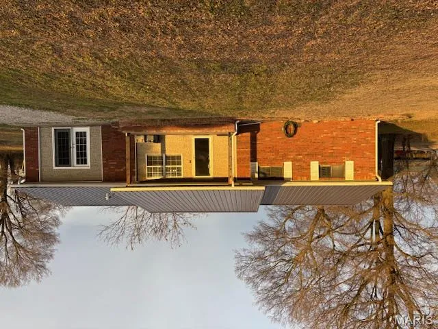 View of front of property with brick siding, a front lawn, and a metal roof