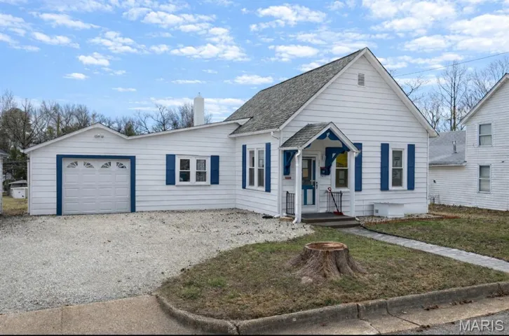 View of front of property with driveway, a chimney, a garage, a front yard, and roof with shingles