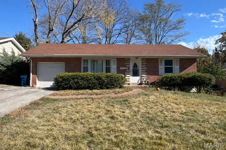 Ranch-style house featuring an attached garage, brick siding, a front yard, and driveway