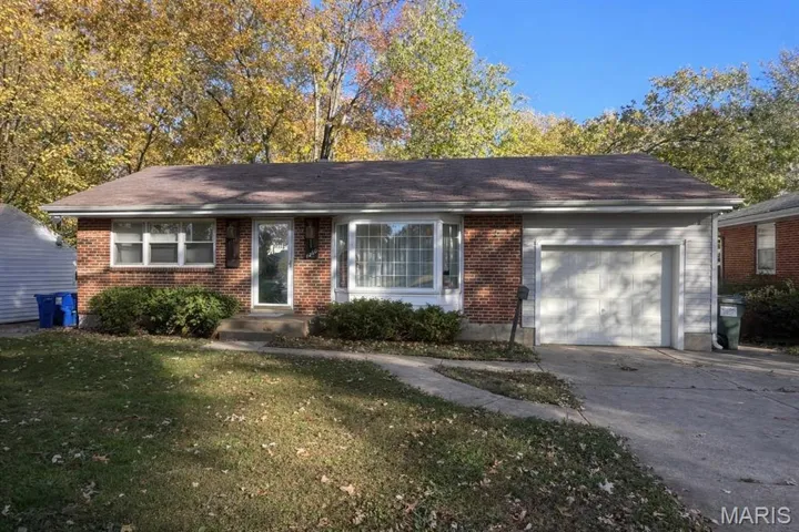 Single story home featuring a front lawn, brick siding, concrete driveway, and a garage