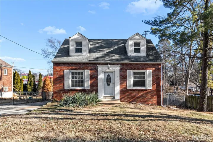 Cape cod house featuring brick siding