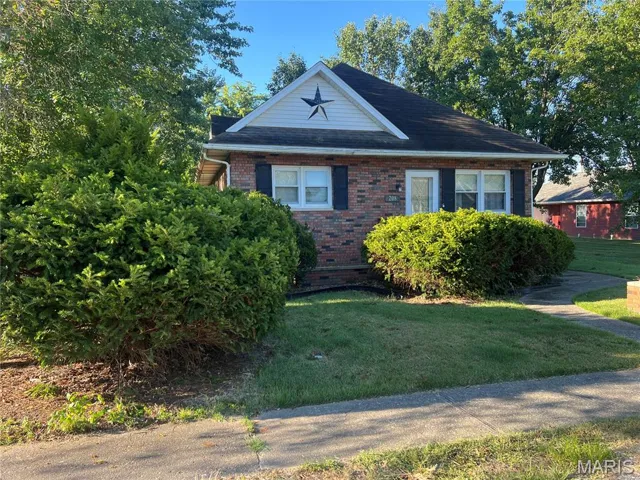 View of front facade with brick siding and a front lawn