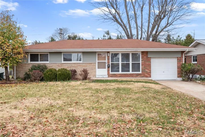 Ranch-style home featuring an attached garage, driveway, a front lawn, and stone siding