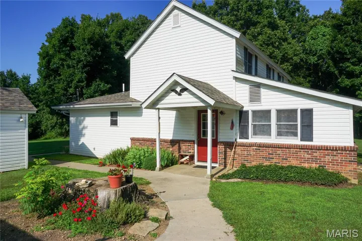View of front facade featuring brick siding, a shingled roof, and a front yard