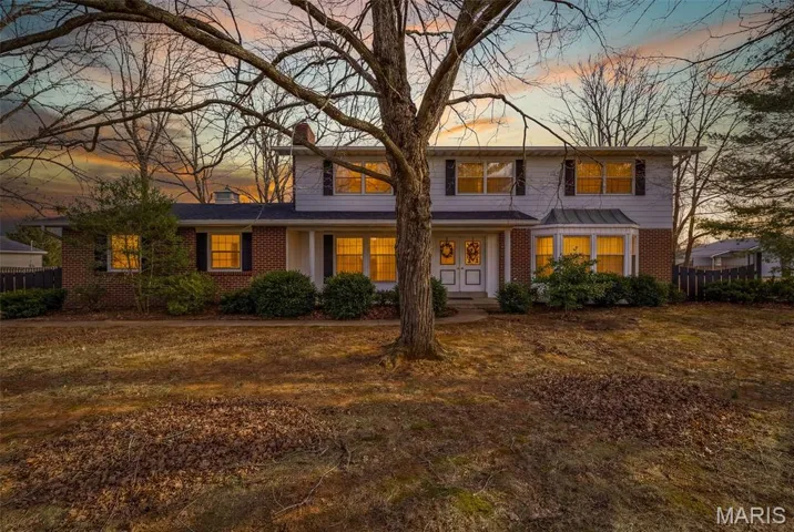 Traditional home featuring a porch, brick siding, and a chimney