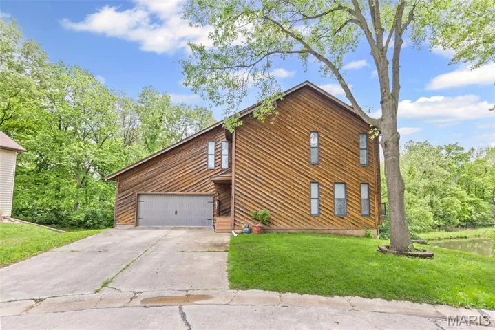 View of front of property with a garage, driveway, and a front lawn