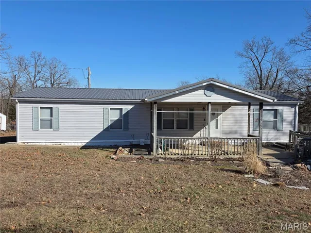 View of front of home with a metal roof, a front yard, and covered porch