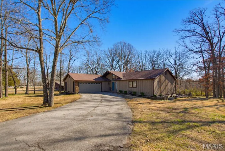View of front of home featuring driveway, a front yard, and a garage
