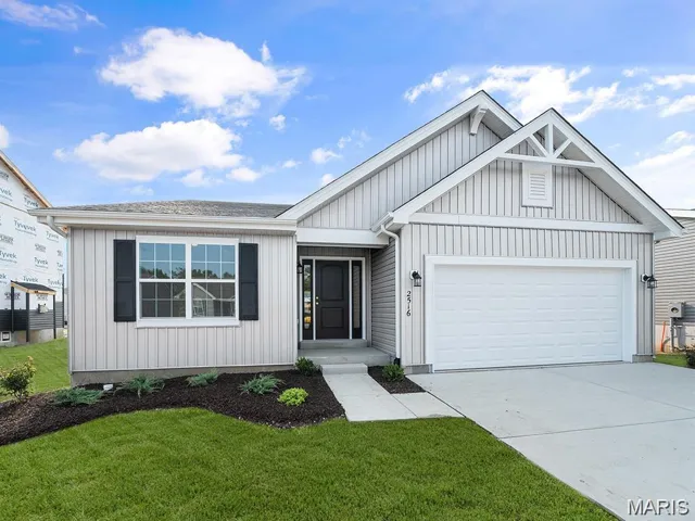View of front of house with an attached garage, a front yard, concrete driveway, and board and batten siding
