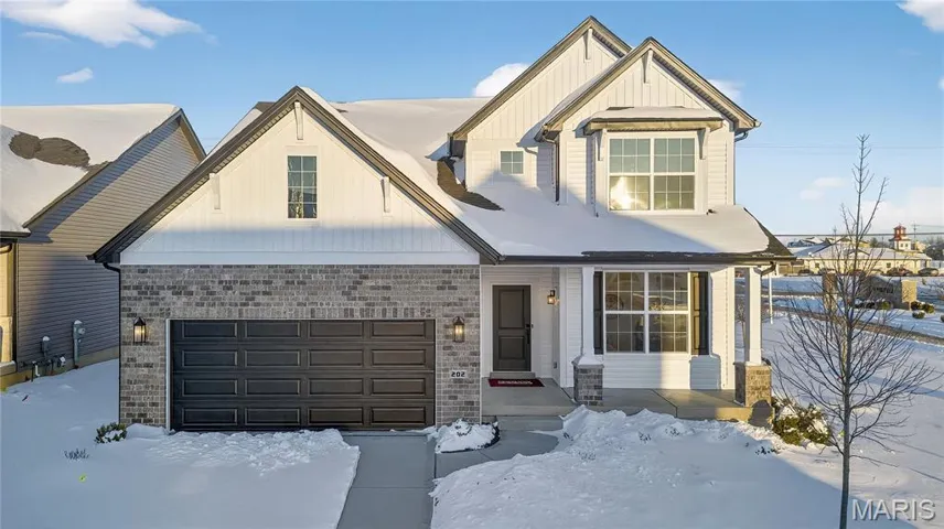 View of front of home with brick siding, a garage, board and batten siding, and a porch