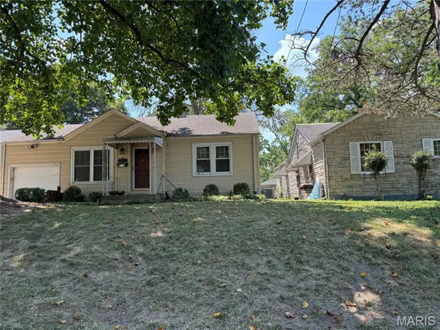 View of front of home with an attached garage, a front lawn, stone siding, and roof with shingles