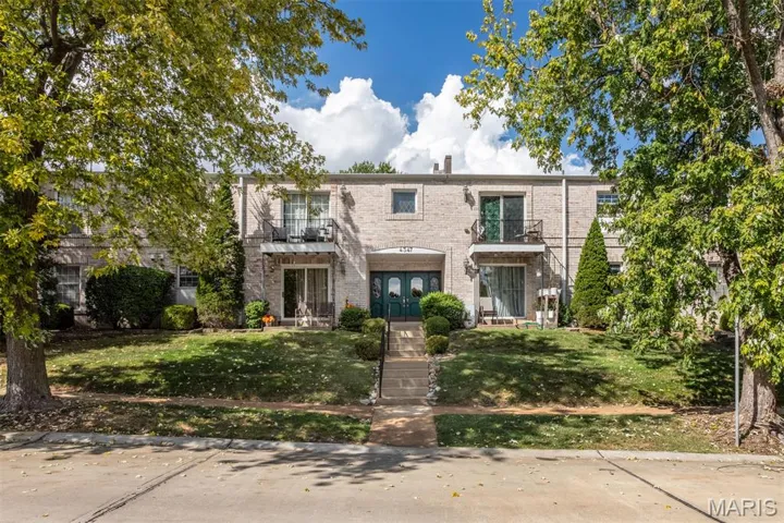 Traditional home with brick siding, a balcony, a front lawn, and a chimney