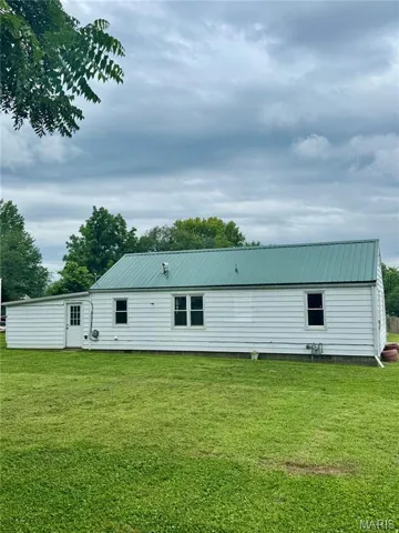 Rear view of property with a lawn and a metal roof