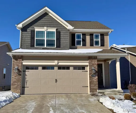 View of front of home featuring an attached garage, covered porch, brick siding, and driveway