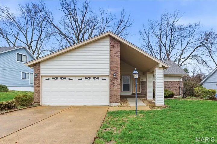 View of front of house with brick siding, concrete driveway, an attached garage, and a front yard