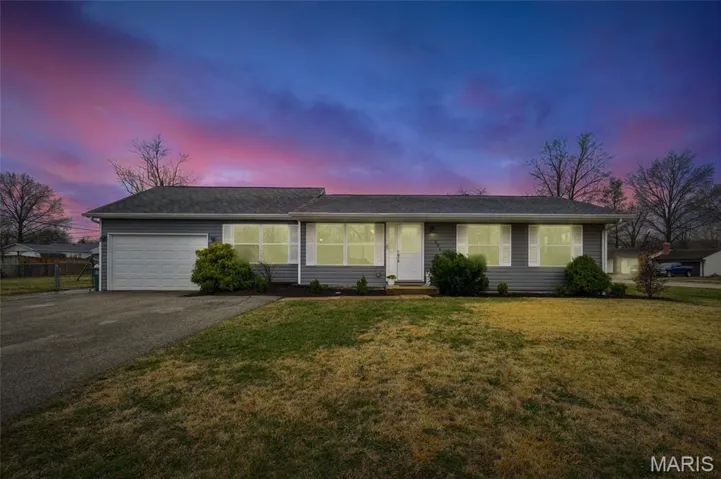 Ranch-style house featuring a yard, a garage, and driveway