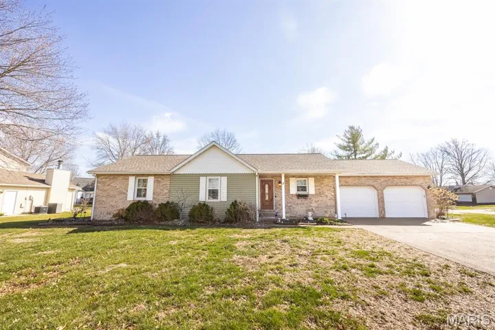 Ranch-style house featuring a porch, an attached garage, concrete driveway, and a front yard