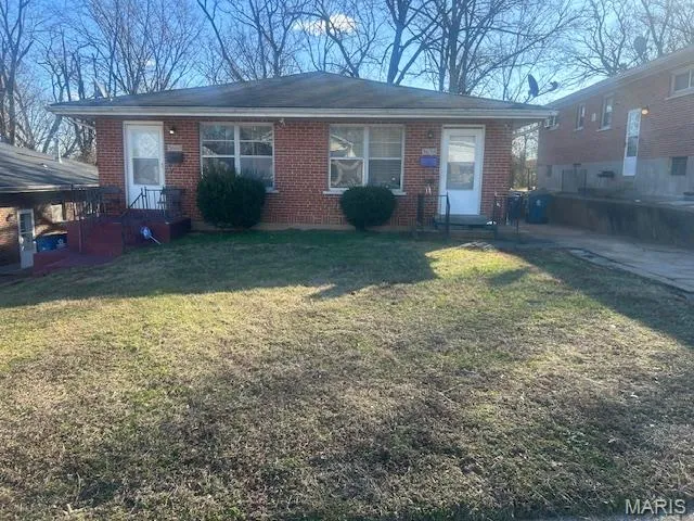 View of front of property with brick siding, a front yard, and a patio
