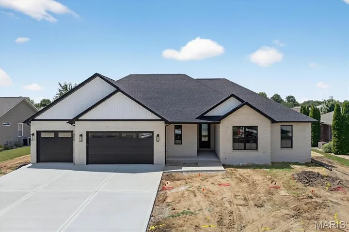 Modern farmhouse style home featuring an attached garage, brick siding, and driveway