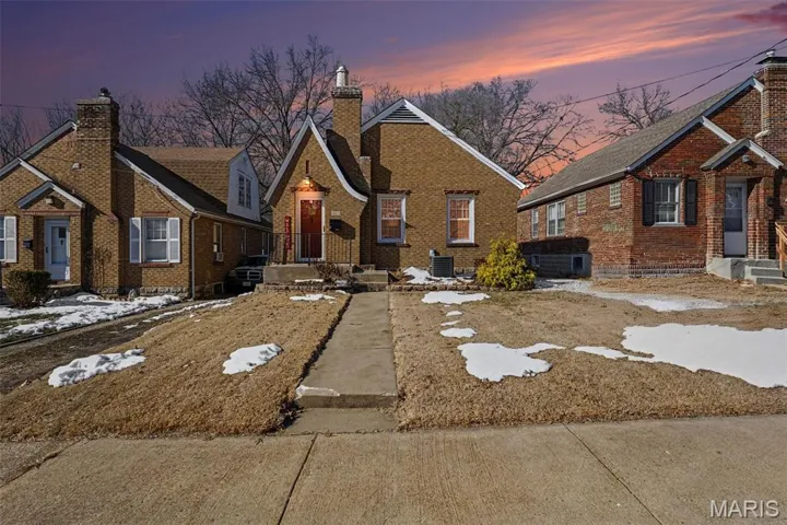 Tudor-style house featuring a chimney and brick siding