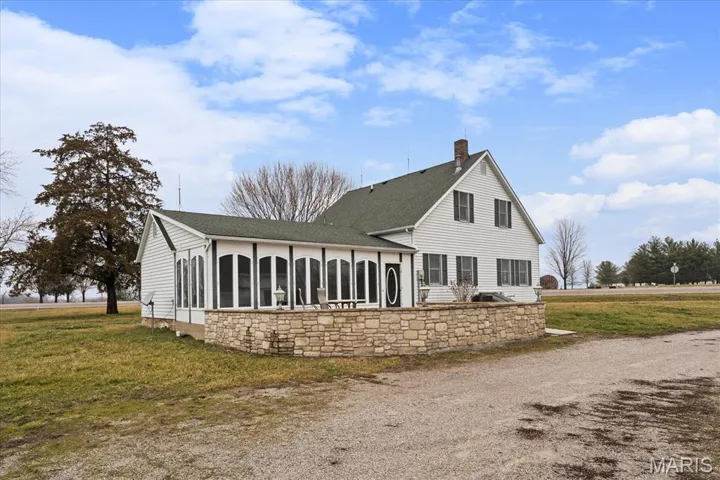 Back of house with a lawn, a chimney, a sunroom, and roof with shingles