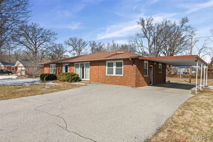 Single story home with brick siding, an attached carport, asphalt driveway, and a front lawn