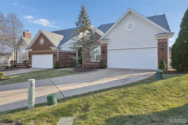 Traditional home featuring driveway and brick siding