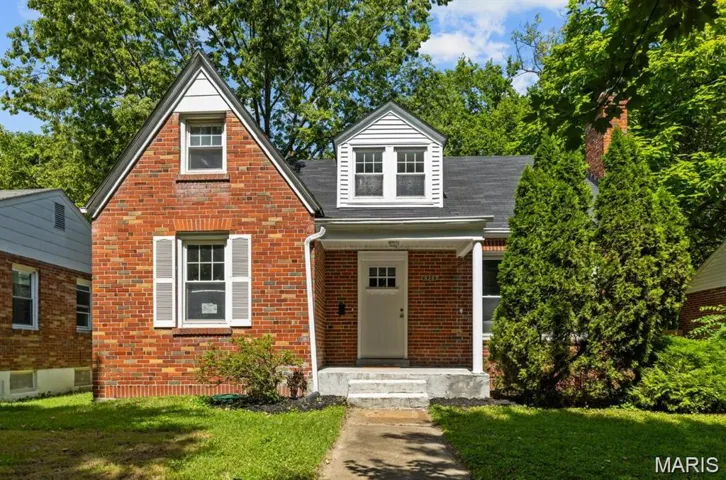 View of front of house with brick siding, a front yard, a porch, and roof with shingles