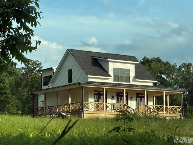 Farmhouse-style home with roof with shingles, board and batten siding, and a large porch