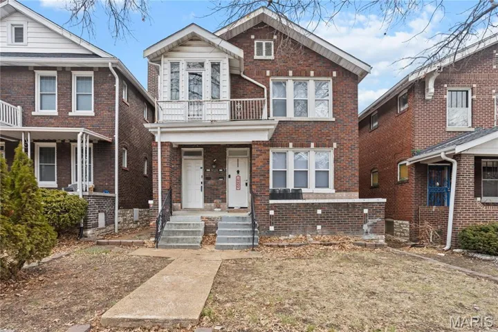 View of front of house with brick siding and a balcony