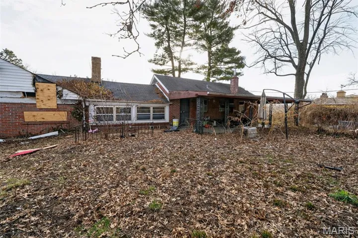 Rear view of house featuring a chimney, brick siding, and a patio