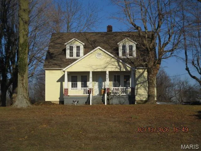 Cape cod house featuring covered porch and a chimney