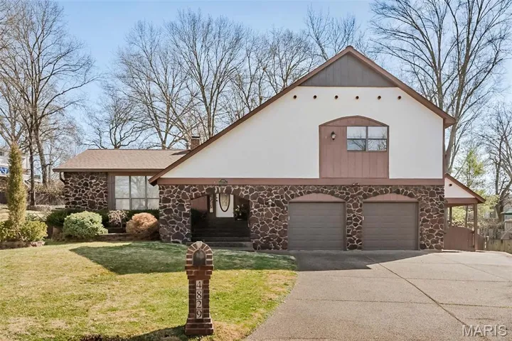 View of front of property featuring stone look siding, attached garage, oversized driveway