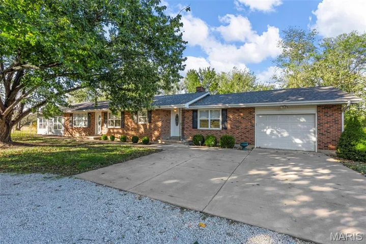 Single story home with driveway, brick siding, an attached garage, and a chimney