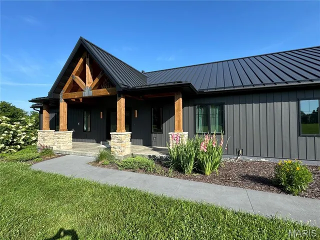 View of front of house with board and batten siding, covered porch, a standing seam roof, and a metal roof
