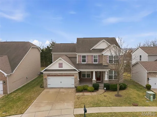 Craftsman-style home featuring a porch, roof with shingles, a front yard, concrete driveway, and an attached garage