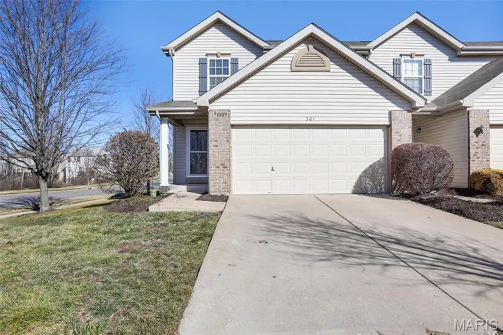 Traditional-style townhouse featuring concrete driveway, a front lawn, brick siding, and a 2 car garage