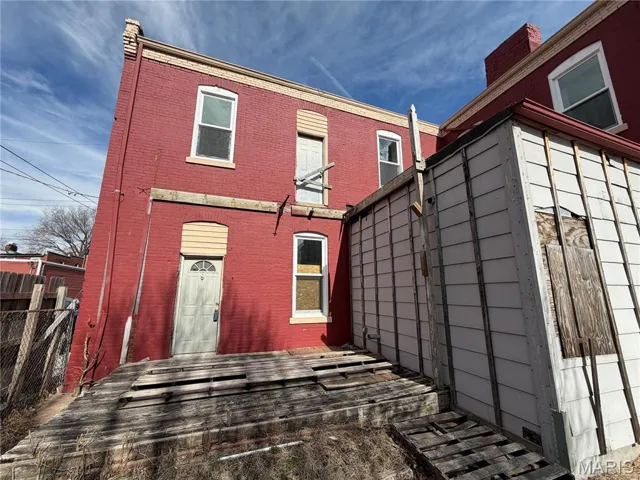 Rear view of property featuring brick siding and a deck