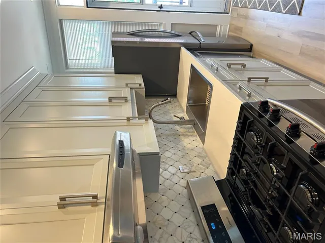 Kitchen with stove, extractor fan, light countertops, light wood-style flooring, and backsplash