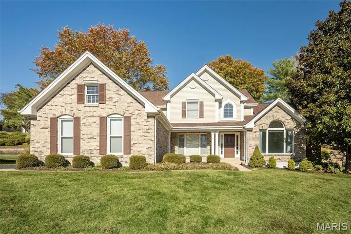 Traditional home featuring brick siding and a front lawn