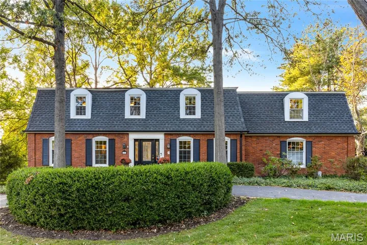 View of front of property featuring mansard roof, brick siding, a shingled roof, and a front lawn